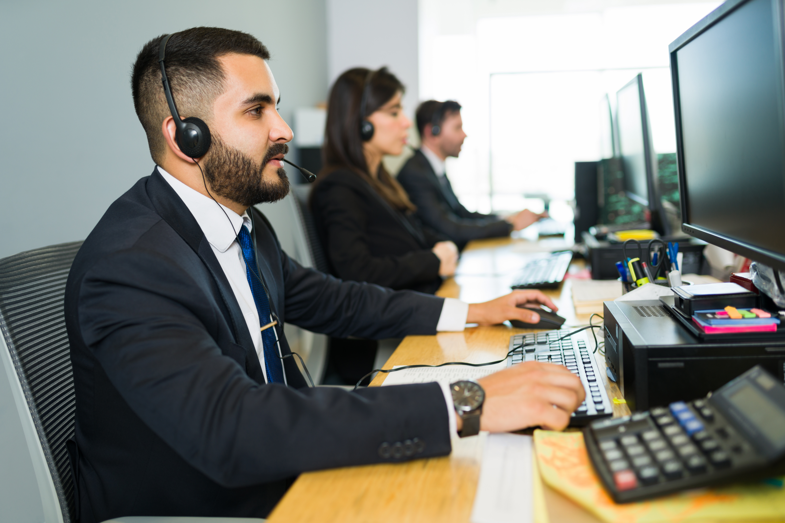 attractive latin executive offering customer service with headset offering tech support busy call center